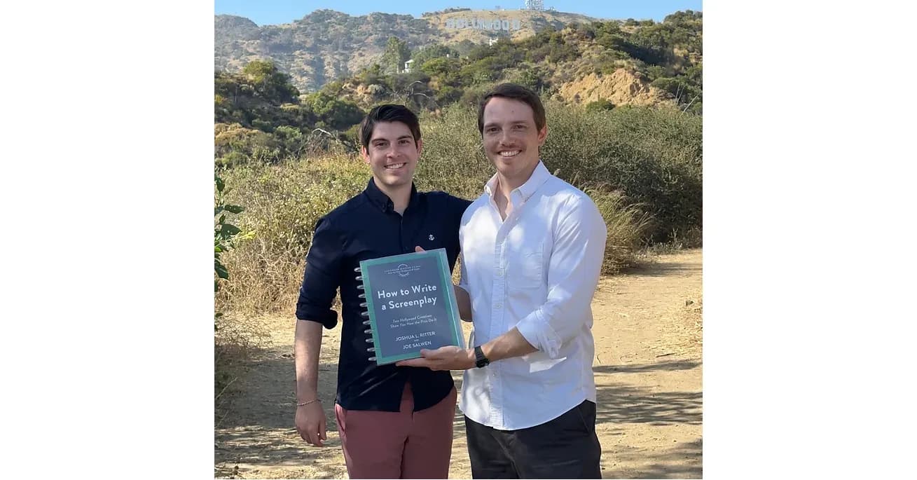 Joshua Ritter and Joe Salwen holding their screenplay workbook in front of the Hollywood sign