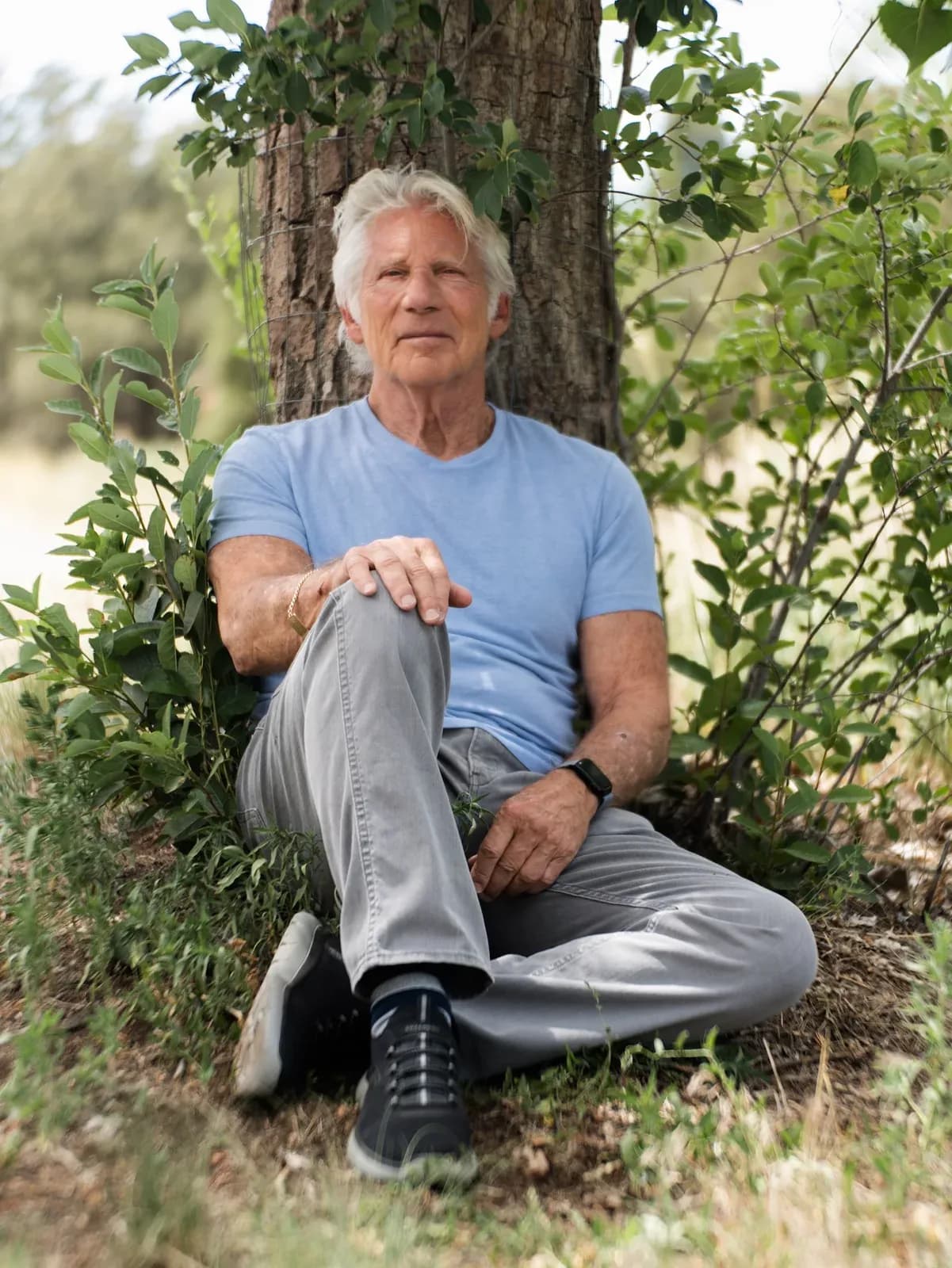 Leon Aryah Lewis, author of Inside Out: A Journey of the Soul, seated against a tree in an outdoor setting