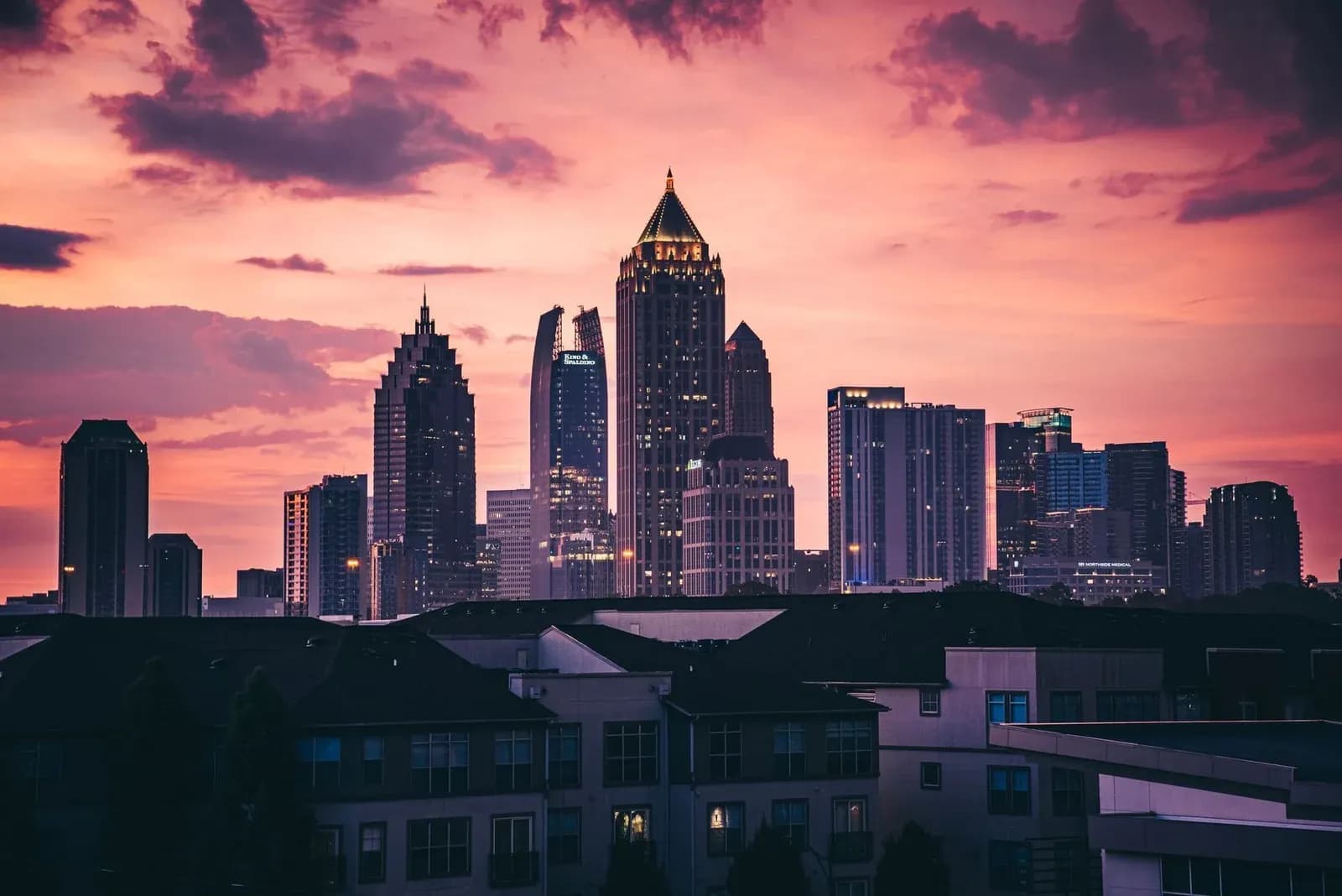 The Atlanta skyline silhouetted against a pink and violet sunset.